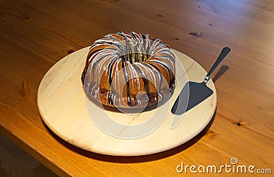 Whole uncut brown sugar coated Bundt cake on white turntable with silver cake shovel Stock Photo