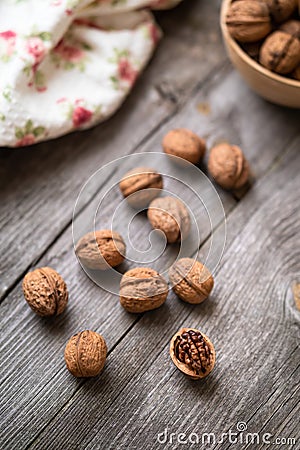 Whole walnuts in a bowl and on rustic old wooden table. Stock Photo