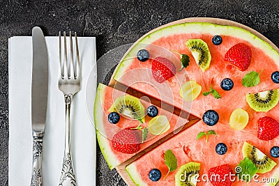 Whole watermelon pizza sliced with fruits, dark background, top view Stock Photo
