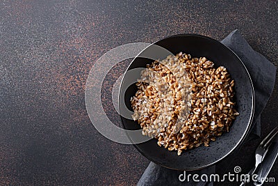 Wholegrain spelt farro in bowl on brown background. Top view Stock Photo