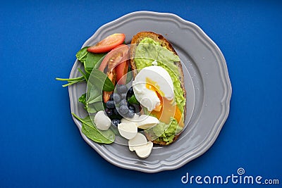 Wholesome tasty full of vitamins and health breakfast with avocado, berries, cheese and tomatoes with basil. Stock Photo