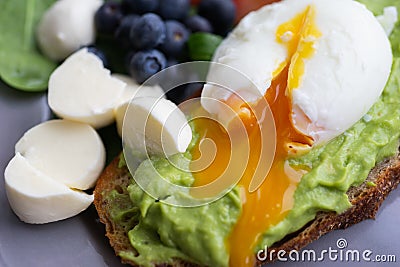 Wholesome tasty full of vitamins and health breakfast with avocado, berries, cheese and tomatoes with basil. Stock Photo