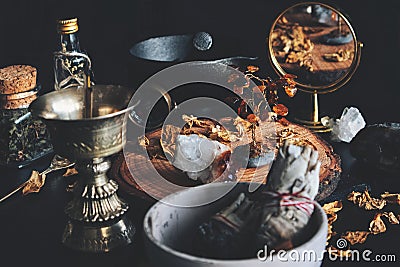 Wiccan witch altar working space. Looks busy and messy, filled with dried herbs, citrine crystal, amber decoration, sage sticks Stock Photo