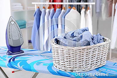 Wicker basket with clothes on ironing board Stock Photo