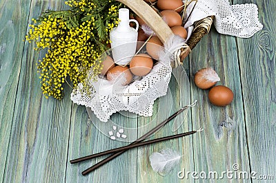 Wicker basket with eggs, branches of mimosa, holy water, church candles and incense Stock Photo
