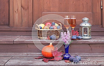 Basket with fruits, rose champagne, lantern, figs, pumpkin and purple spirea are on steps of rustic wooden ladder Stock Photo