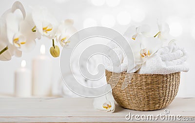 Wicker basket with spa towels on table over abstract background Stock Photo