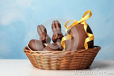 Wicker basket with sweet chocolate Easter eggs and bunnies on table Stock Photo
