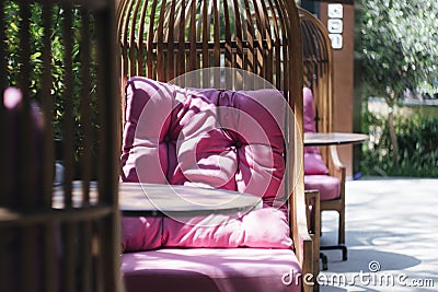 Wicker chair with pink pillows on a summer veranda in a cafe Stock Photo
