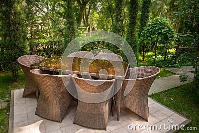 Wicker chairs and table are in the garden near trees Stock Photo