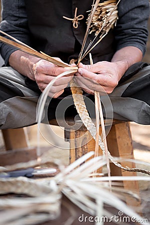 Old wicker craftsman with hands working in isolated foreground Stock Photo