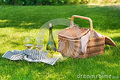 Wicker picnic basket, fruits and bottle of wine with glasses on napkin Stock Photo