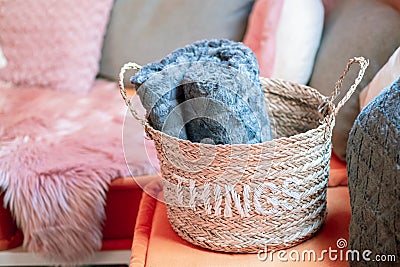 Wicker storage basket with woolen blanket inside and cushions Stock Photo