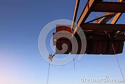Rope access worker inspector wearing fall safety harness working abseiling in rope transfer position Stock Photo