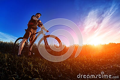 Wide angle of the cyclist standing on the trail on the field against beautiful landscape. Stock Photo