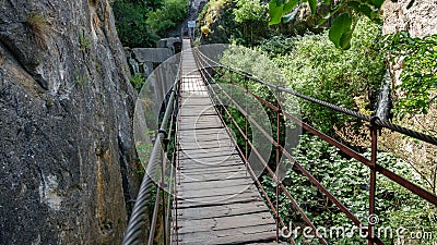Iron and wooden suspension bridge in canyon between vertical rocks Stock Photo