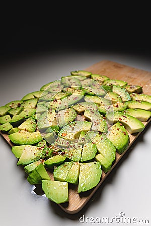 Wide Angle Large slices of sliced ripe avocado lie textured on a wooden cutting board. Sprinkled with spices. Healthy Stock Photo