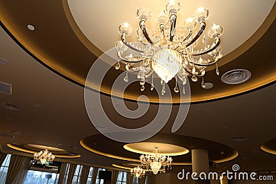 A few pendant lighting hanging from a cornice ceiling shinning warm amber golden light rays Stock Photo