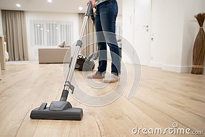 Wide angle photo of woman housewife or maid or service worker hoovering with vacuum cleaner in bright luxury appartment. Stock Photo