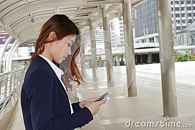 Wide angle shot of Young attractive business woman using mobile phone in her hands at urban outdoor background. Stock Photo