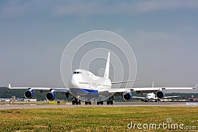 Wide body airplane taxiing on the main taxiway and then another plane Stock Photo