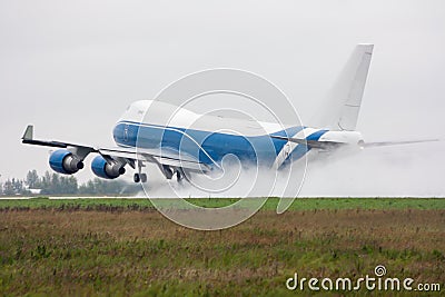 Wide body cargo airplane takes off in a heavy rain leaving behind a cloud of splatter Stock Photo