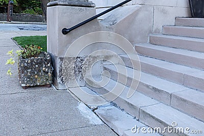 Wide concrete entry stairs on a church exterior, black metal pipe railing and stone planter alongside a concrete sidewalk Stock Photo