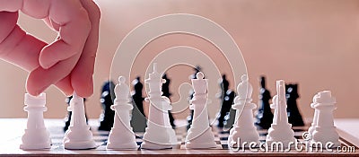 A wide cropped image of a child s hand placing chess pieces on a chessboard Stock Photo