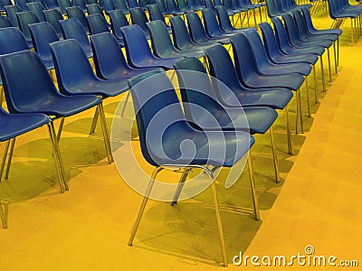 Wide empty seats rows blue chairs on yellow floor Stock Photo