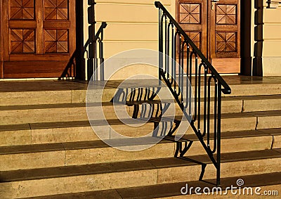 wide exterior stone stairs. deep treads and defined vertical risers. decorative painted black wrought iron railing Stock Photo