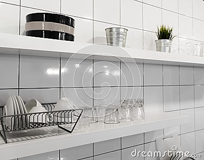 Wide kitchen shelves and wall shelving for storage and display. White wooden shelf and budget lightweight dish rack with dishes, Stock Photo