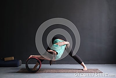 Woman doing yoga asana Wide Legged Forward Bend using special wheel. Stock Photo