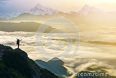 Wide mountain panorama. Small silhouette of tourist with backpack on rocky mountain slope with raised hands over valley covered Stock Photo