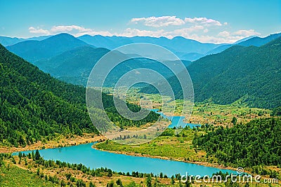 Wide mountain river among dense overgrown forests and hills Stock Photo