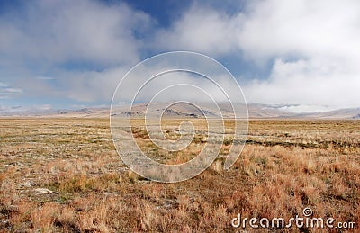 A wide mountain steppe meadow with yellow grass and mist clouds on the Ukok plateau Stock Photo