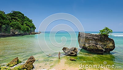 A wide-screen view of a girl standing in the water at padang padang beach in bali Stock Photo