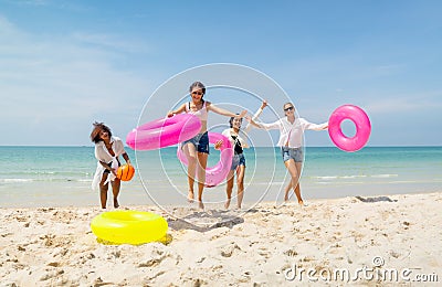 Wide shot group of teen girls bring swimming ring and run from the sea back to the beach during holiday or vacation relaxation Stock Photo