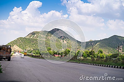 Wide shot of indian highway with trucks, cars, bikes, motorcycle and more on a wide asphalt road with green plants Editorial Stock Photo