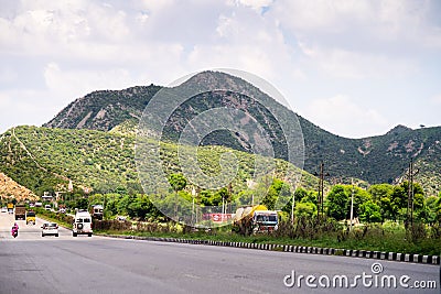 Wide shot of indian highway with trucks, cars, bikes, motorcycle and more on a wide asphalt road with green plants Editorial Stock Photo