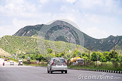 Wide shot of indian highway with trucks, cars, bikes, motorcycle and more on a wide asphalt road with green plants Editorial Stock Photo