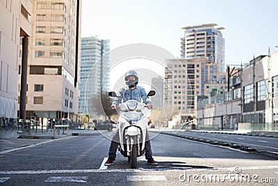 Wide shot of a young motorcyclist stopped at a traffic light in Barcelona. The man riding his scooter through Stock Photo