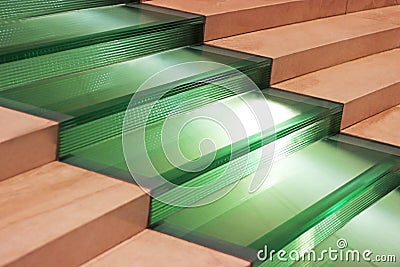 wide staircase with green glass steps between brown stone steps Stock Photo