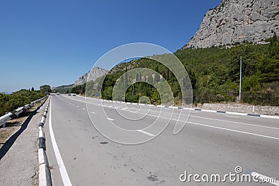 A wide track against the backdrop of endless deciduous forests and huge rocky mountains Stock Photo