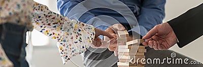 Wide view image of three business people making a tower of wooden pegs Stock Photo