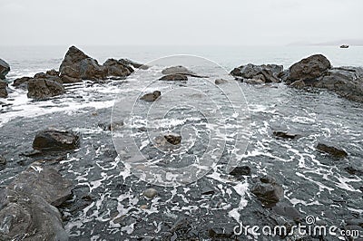 Wide view of waves beating on beach. Rocky sea shore Stock Photo