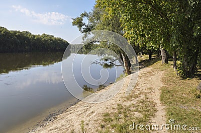 Wide yellow river is slow flowing. Early autumn. Sunny weather and brightgreen trees on the banks fron the both sides Stock Photo