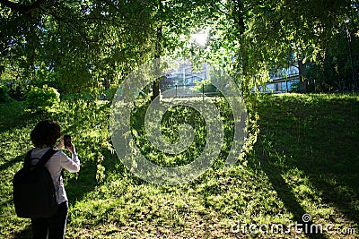 Wideshot of woman taking a snpashot of sunset in park Stock Photo