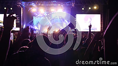 Wiele ręki podnosić fan w jaskrawych światłach scena, tłumu ludzie macha ręki i chwycie, dzwonią z cyfrowymi pokazami zbiory Wiele ręki podnosić fan w jaskrawych światłach scena, tłumu ludzie macha ręki i chwycie, dzwonią z cyfrowymi pokazami zbiory