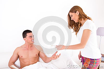 Wife giving husband coffee in bed Stock Photo