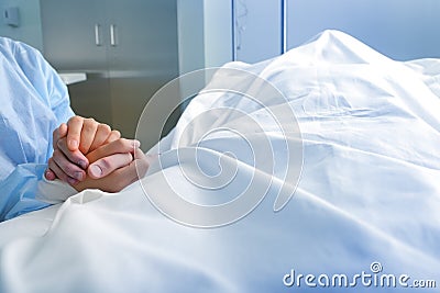 Wife holds the hand of the deceased spouse in the hospital Stock Photo